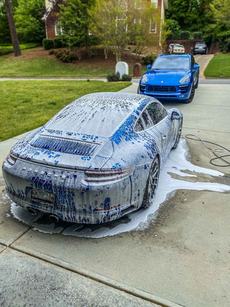 Sports car under thick white foam in a driveway