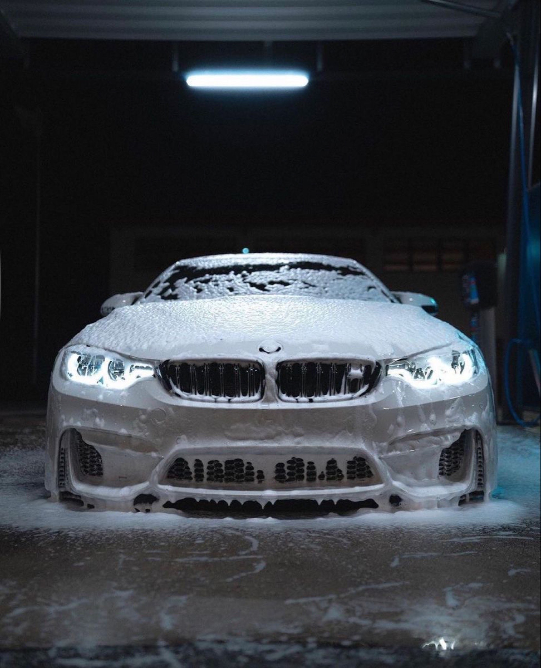 Front of a car covered in foam under low light